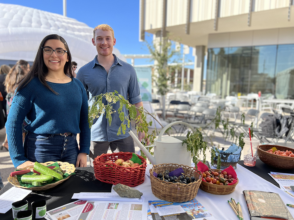 Two ASU students host a table with fresh vegetables.