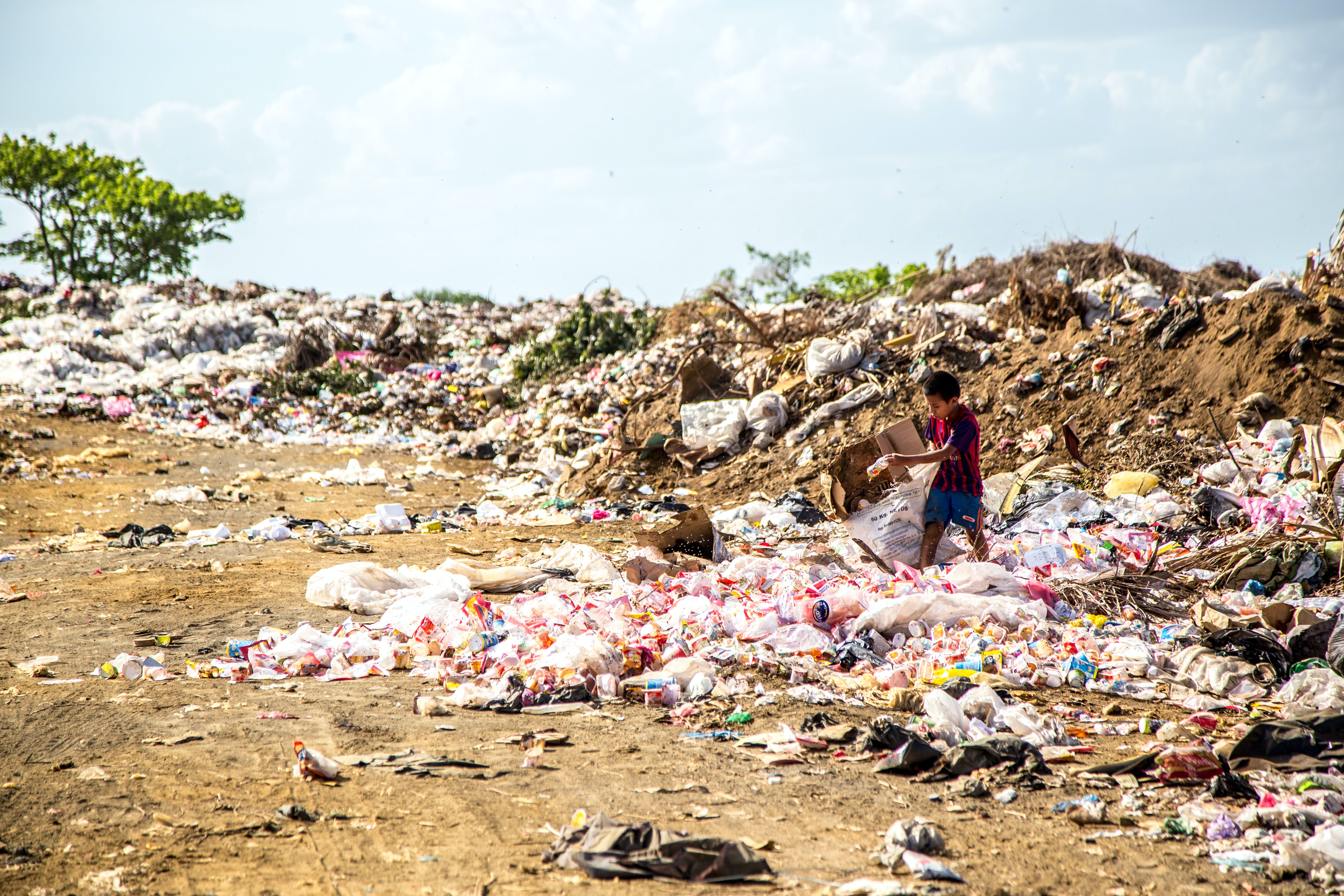 A boy walks away from a huge local trash dump.