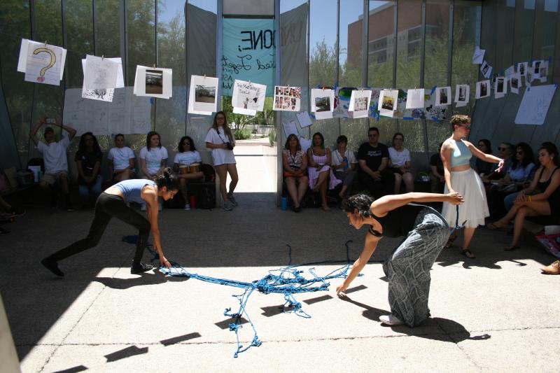 Students doing performative piece under a banner of images