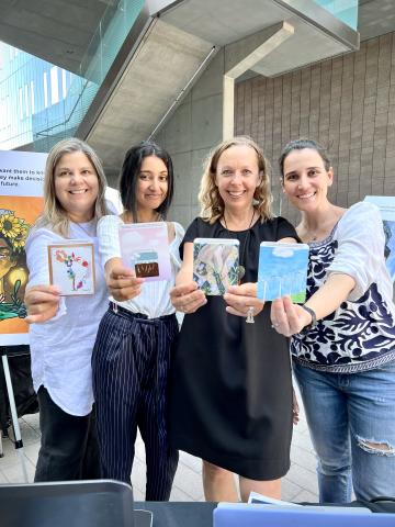 Four women standing together and holding out cards from the Turn It Around Cards deck.